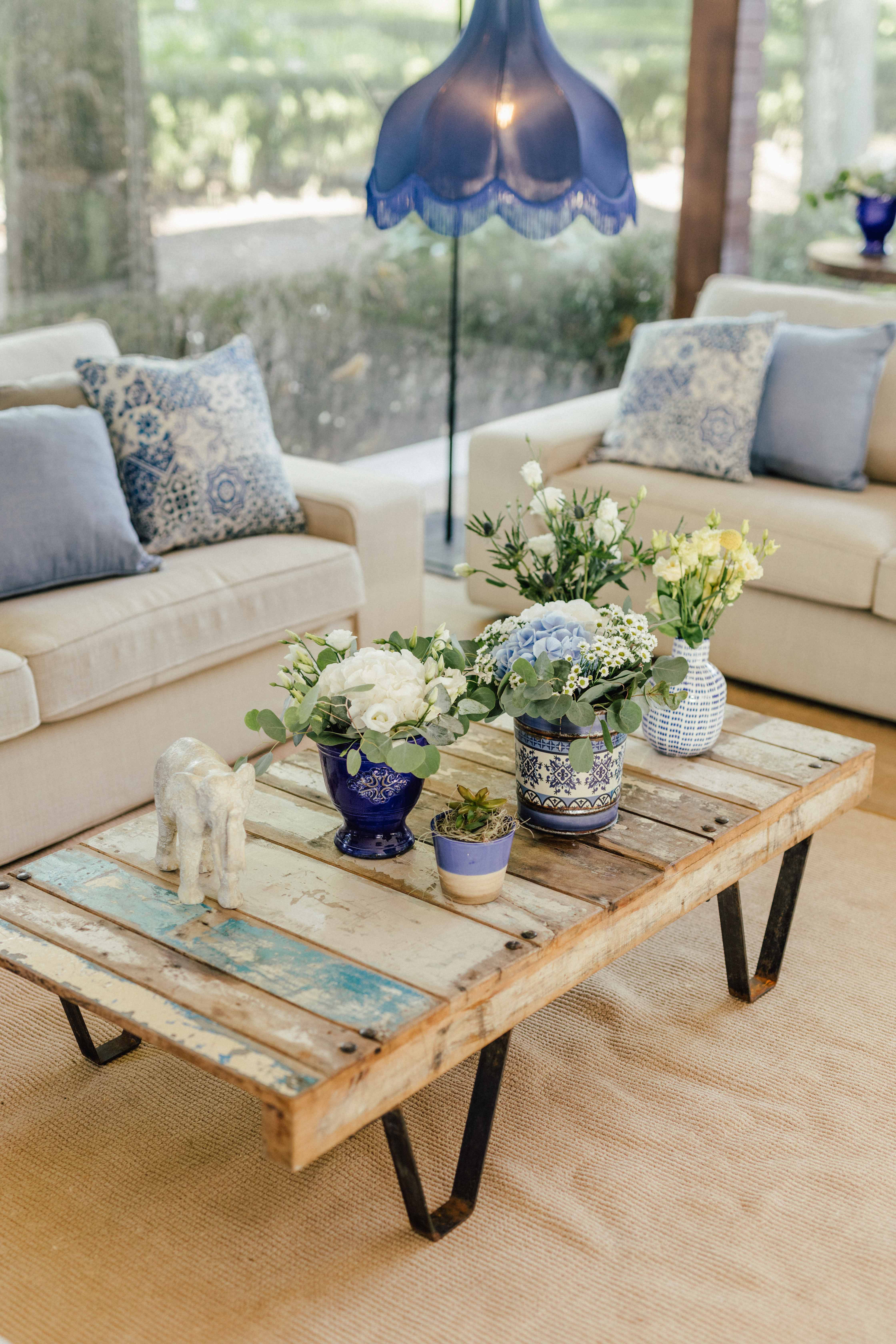 Lounge interior com candeeiro em vidro cobalto, almofadas com padrão de azulejo português, sofás creme, vasos cerâmicos em azul e branco