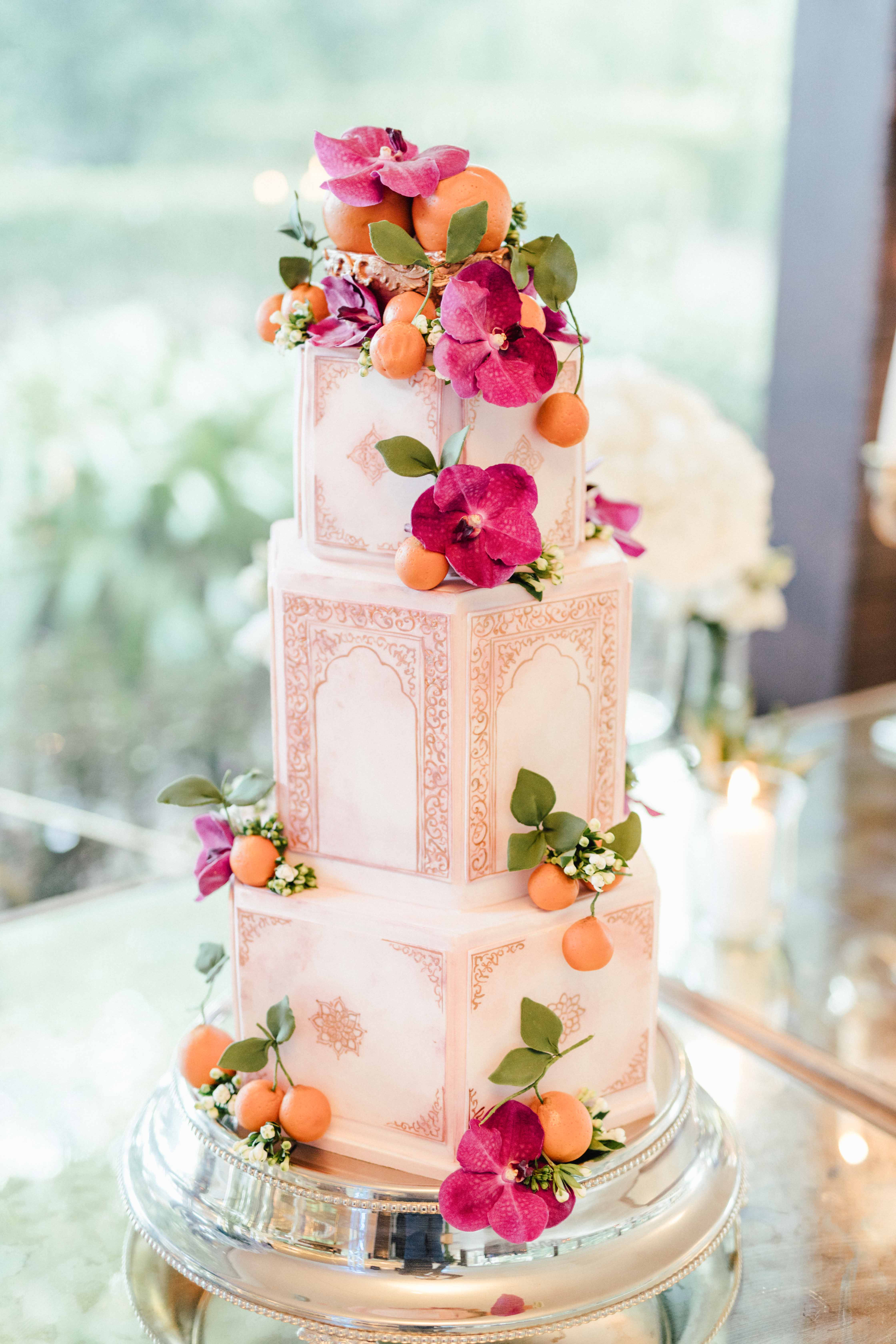 Bolo de três andares com decoração desenhada à mão em estilo Mughal, com orquídeas fúchsia e laranjas pequenas