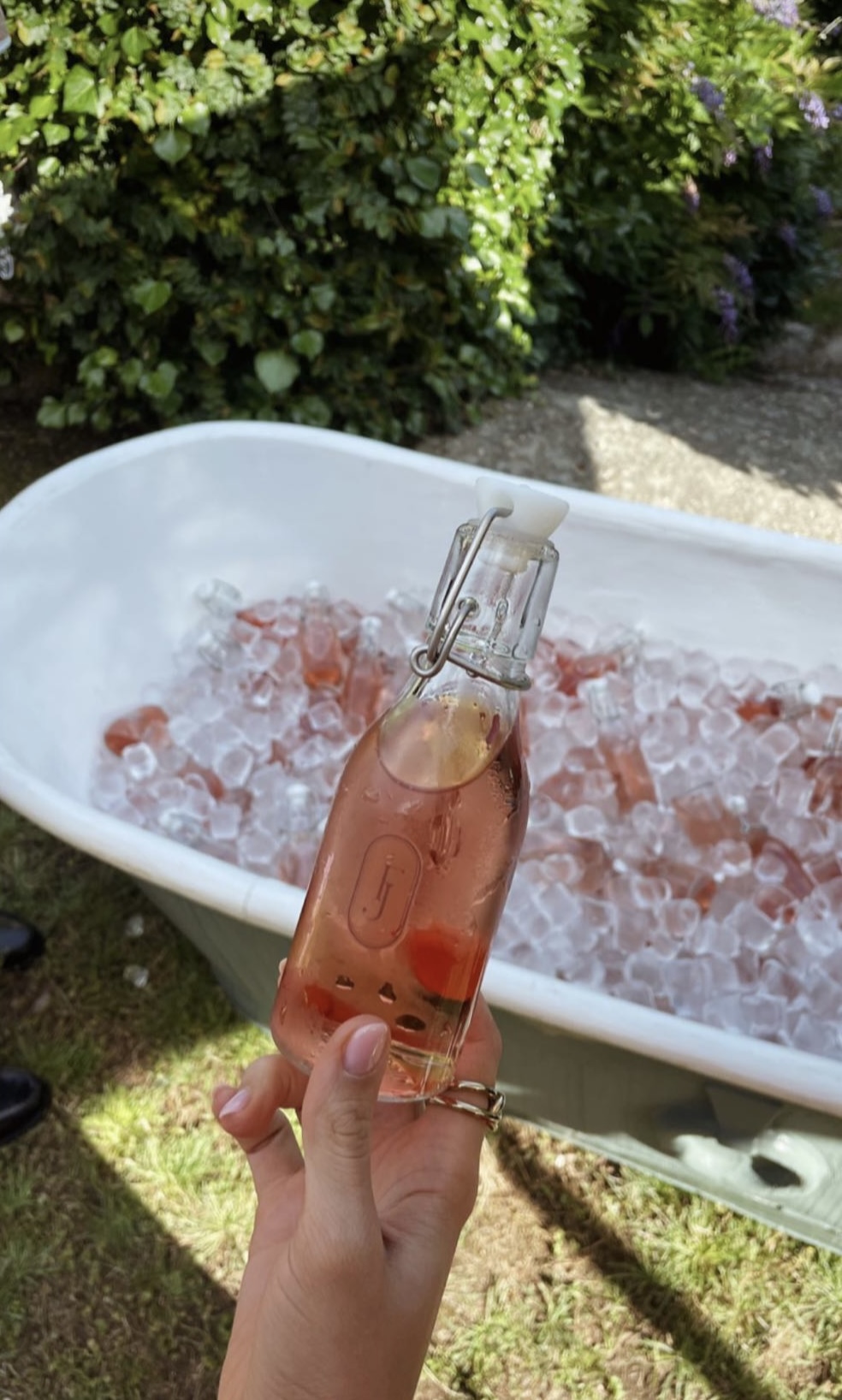 A hand holding a small pink bottle with a porcelain stopper.