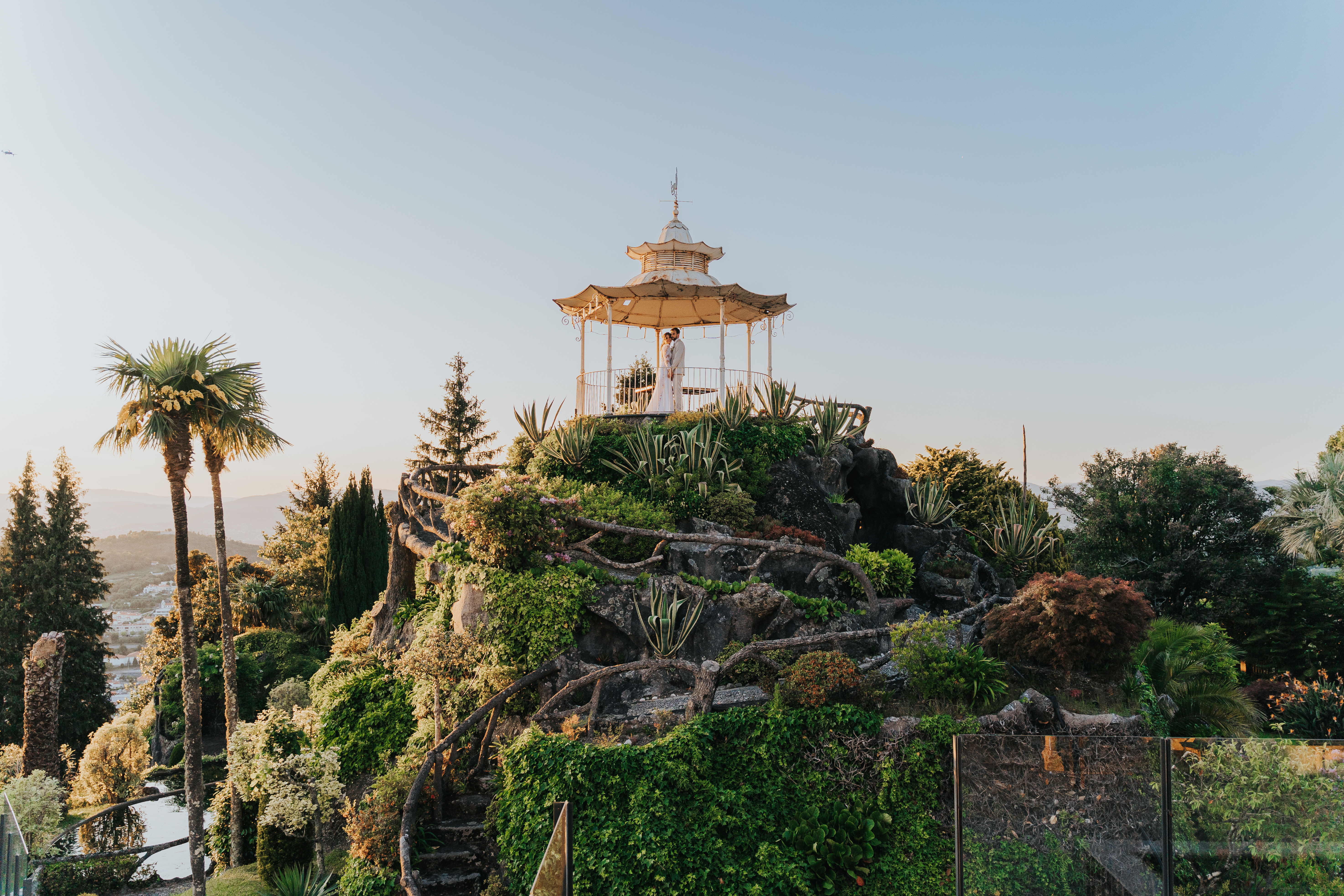 Templete oriental no topo de um jardim romântico, com Rita e Hernani dentro do quiosque, ao pôr-do-sol