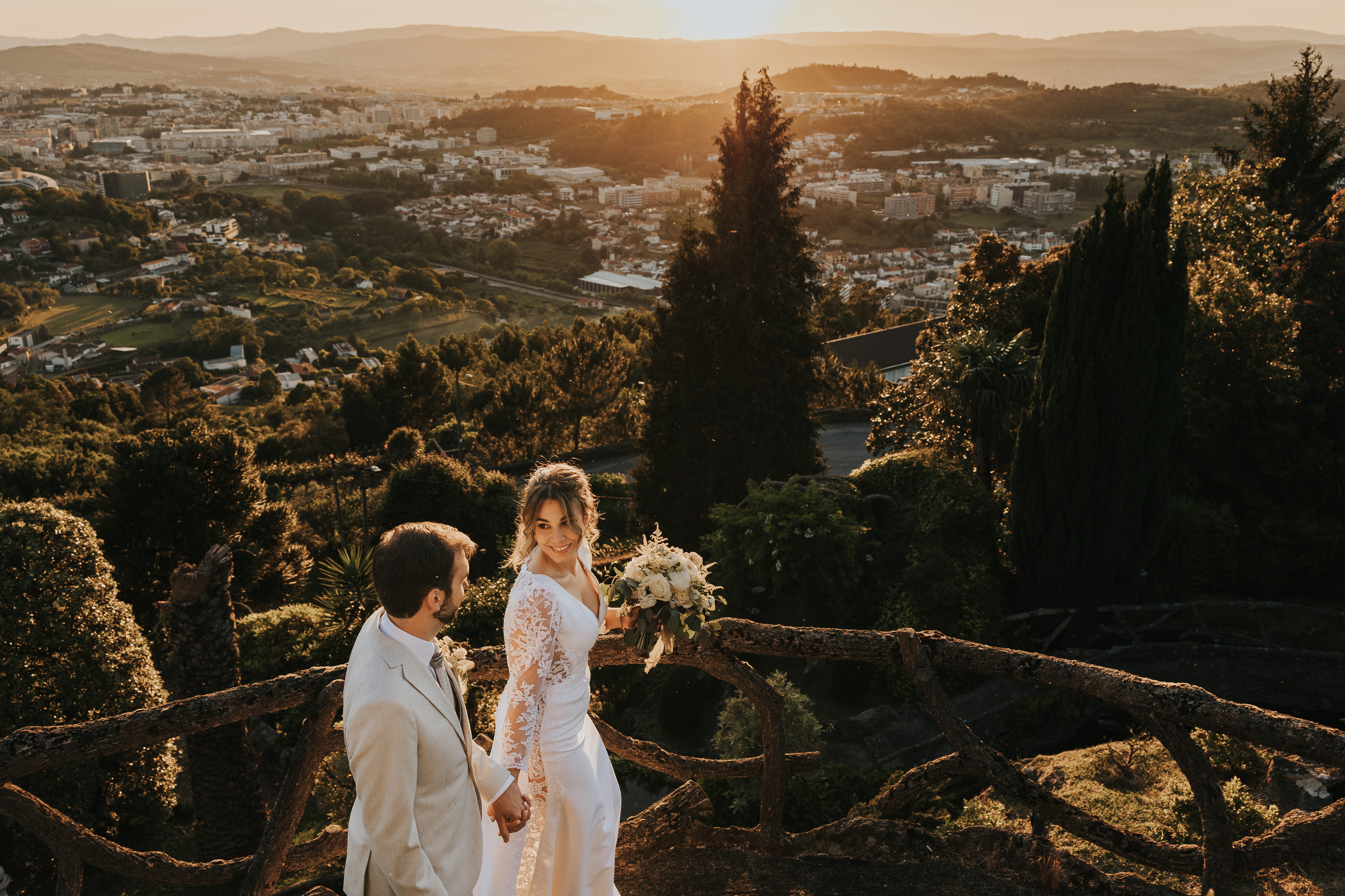 Rita e Hernani no miradouro do jardim ao pôr-do-sol, com Braga estendida ao fundo, a noiva olhando para a câmara